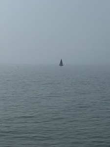 lonely, dark sailboat on a lake in haze